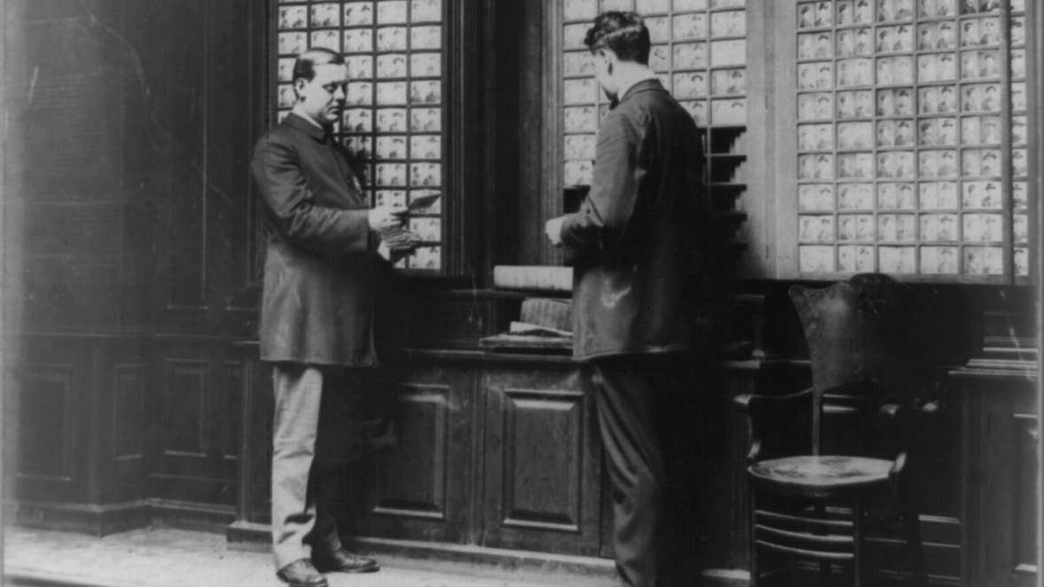 Arquivo de fotografias de identificação da polícia de Nova York em 1909, com dois homens diante da Rogues’ Gallery. Ilustrativa ao artigo Uma introdução aos registros visuais e às práticas de identificação e investigação.