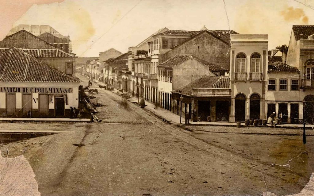 A fotografia no Rio Grande do Sul: vista da Rua Voluntários da Pátria, em Porto Alegre, registrada pelos irmãos Ferrari na década de 1890, com casario e circulação na via.